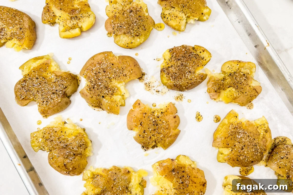 Smashed potatoes sprinkled with salt, pepper, and oil before roasting.