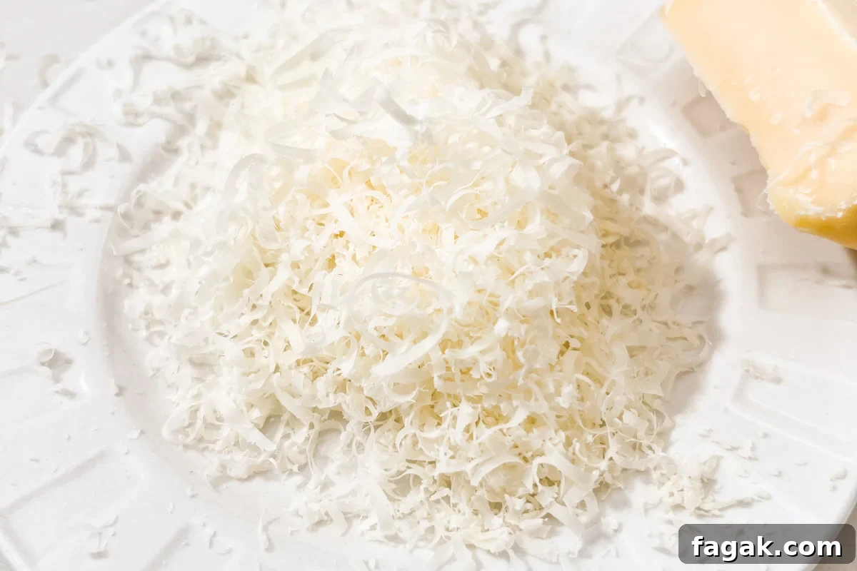 Microplaned parmesan cheese in a fluffy pile on a white plate.