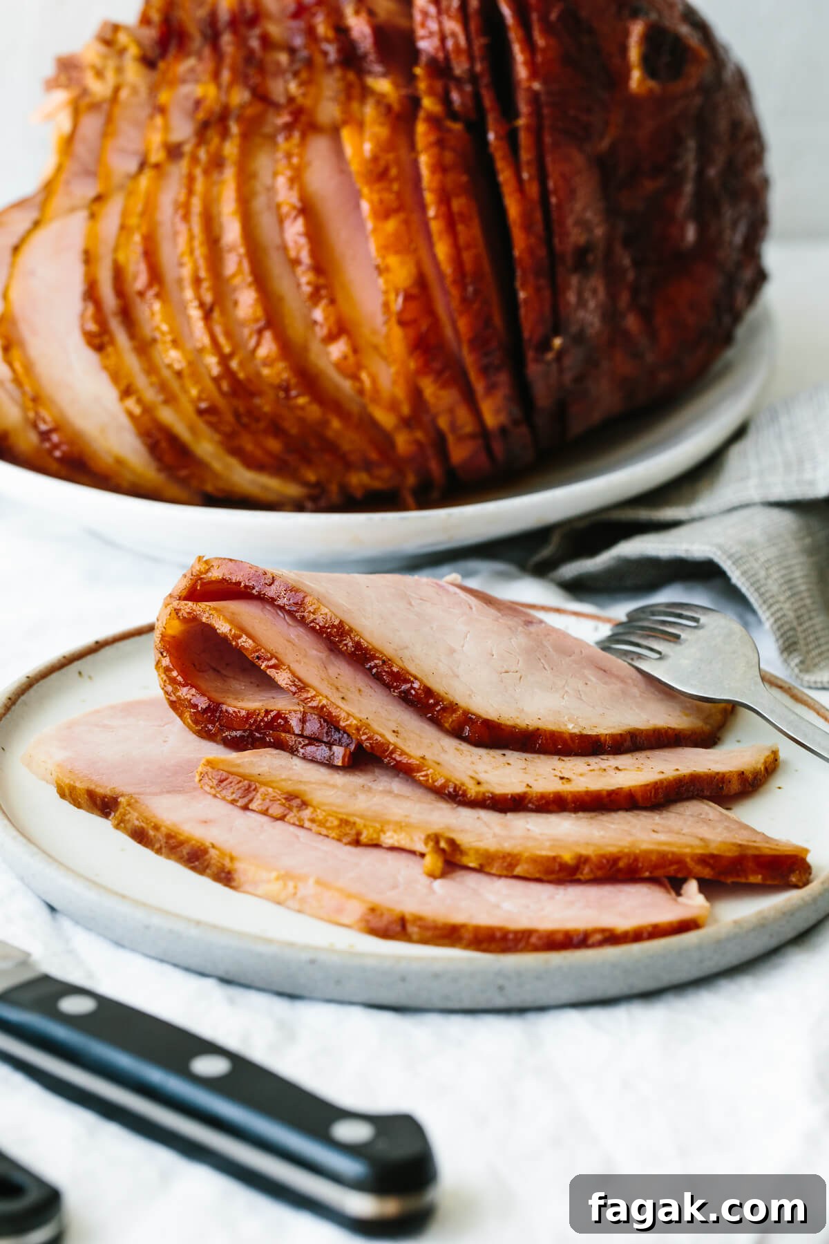 Sliced honey baked ham on a plate with a fork