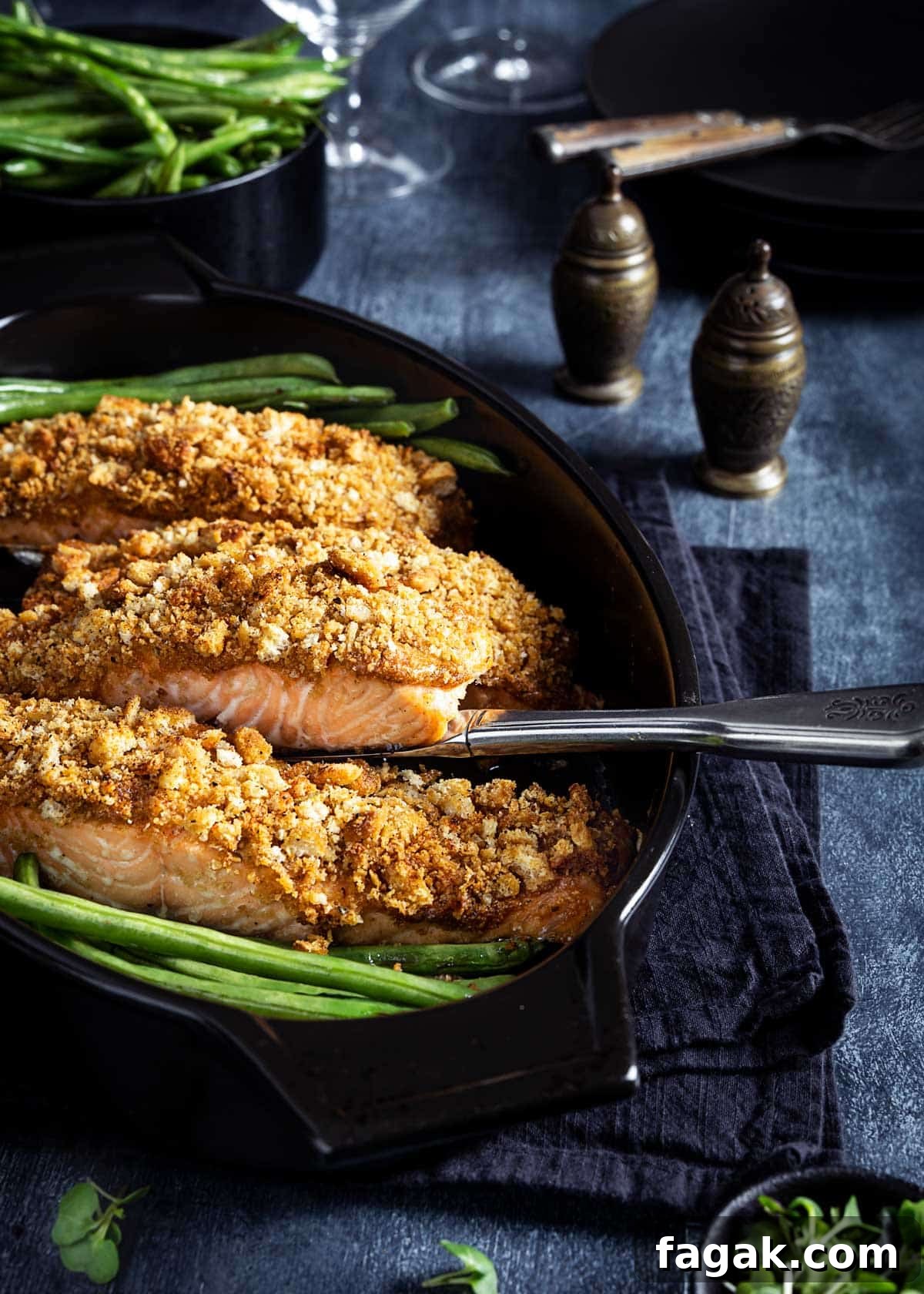 Salmon filets with parmesan crust in a black baking dish with green beans.