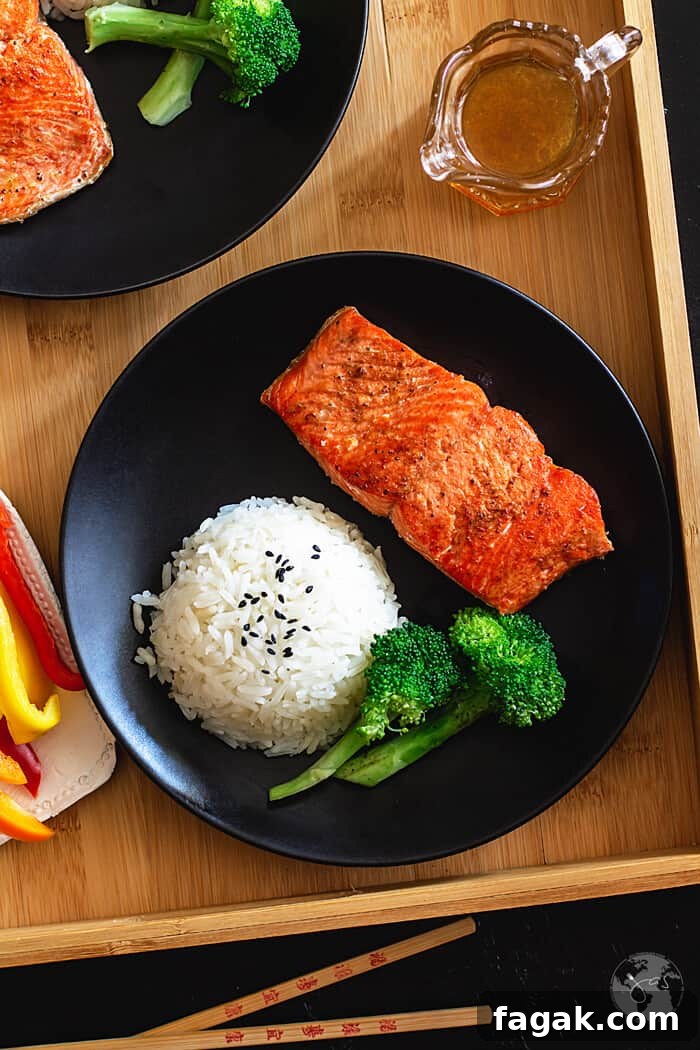 Salmon filet on a black plate with a round of rice