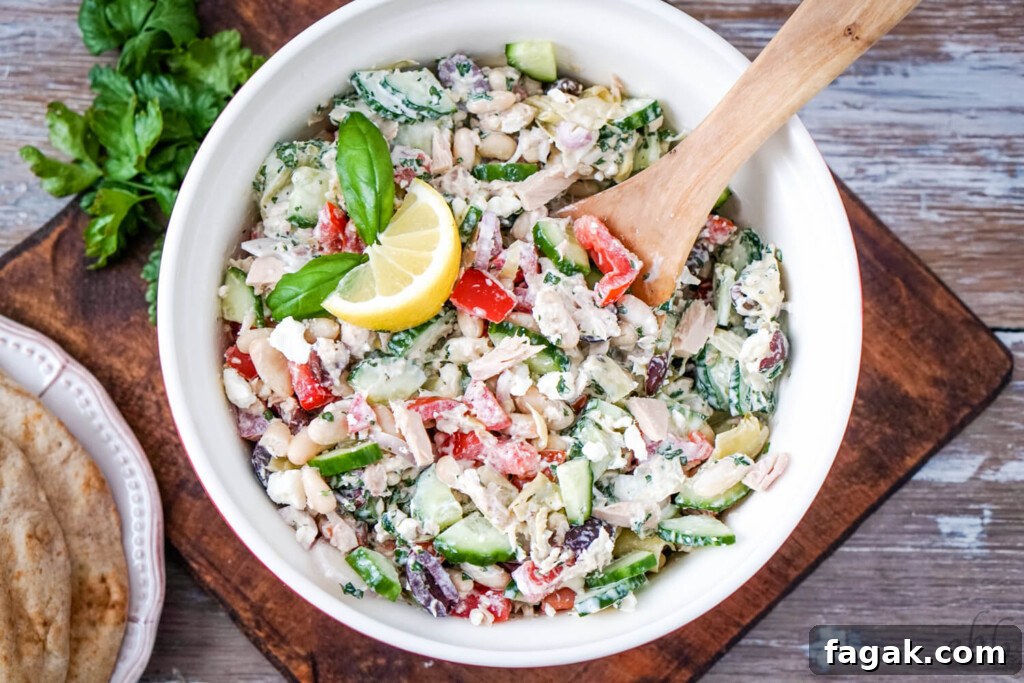 A red bowl of Mediterranean Tuna salad with a stack of pitas to one side.