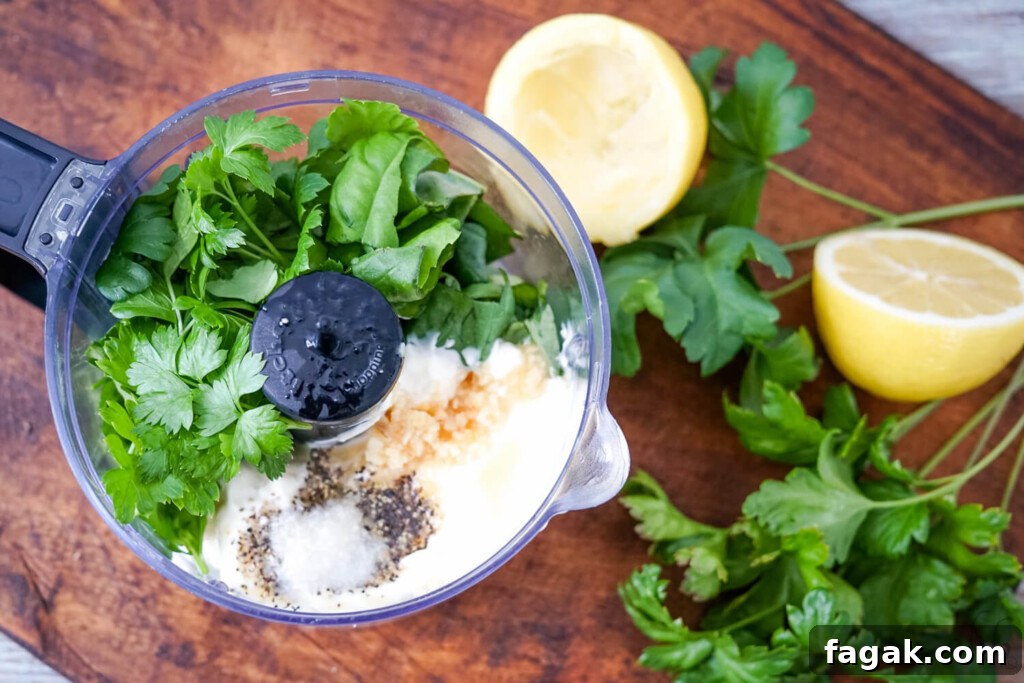 A food processor with the ingredients for the creamy herbed lemon dressing with mayo.