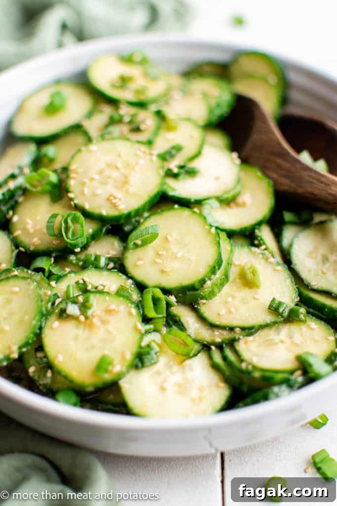 Large bowl of sliced cucumbers with Asian dressing.