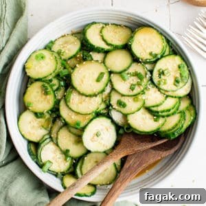 Top down view of a plate of cucumber salad with two wooden spoons.