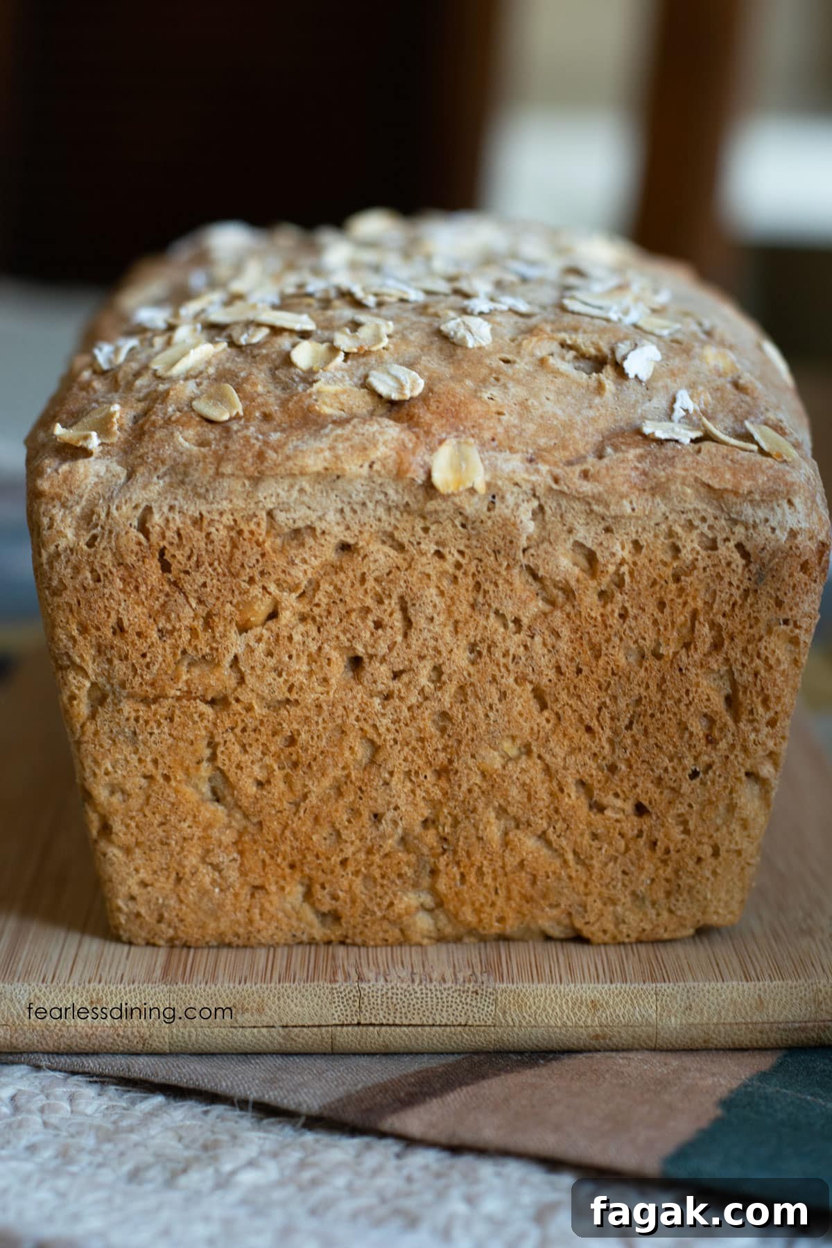The front view of an unsliced loaf of gluten free oat bread on a cutting board.