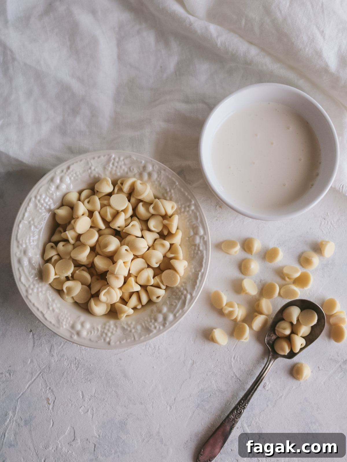 overhead view of a small bowl of white chocolates and a cup of heavy cream to make white chocolate ganache.