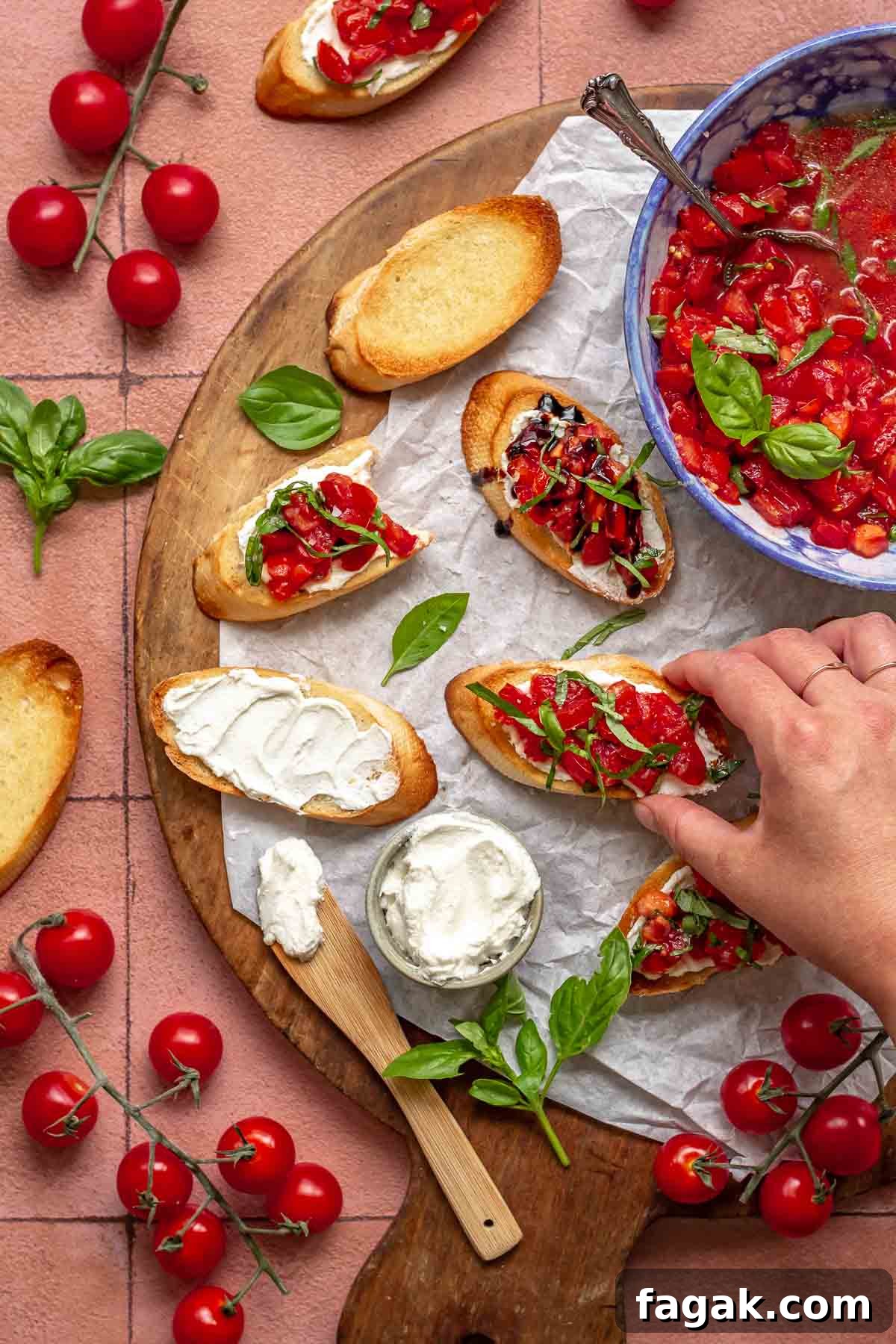 Goat cheese bruschetta on a board with fixings. A hand reaches in to remove one.