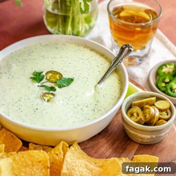 Jalapeno ranch dip in a bowl with chips and jalapeños on the side.