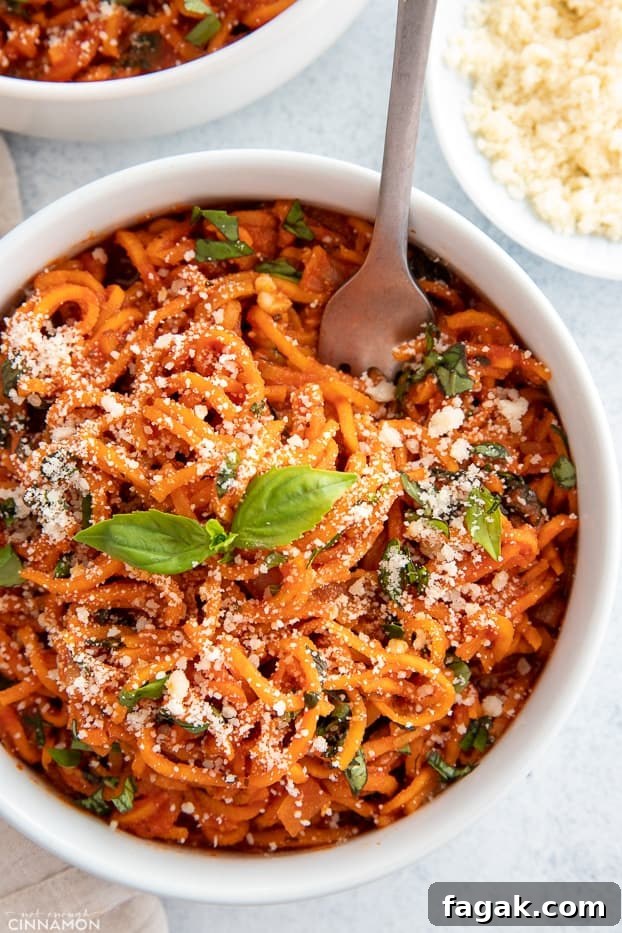overhead shot of a bowl of sweet potato pasta tossed with tomato sauce sprinkled with parmesan cheese