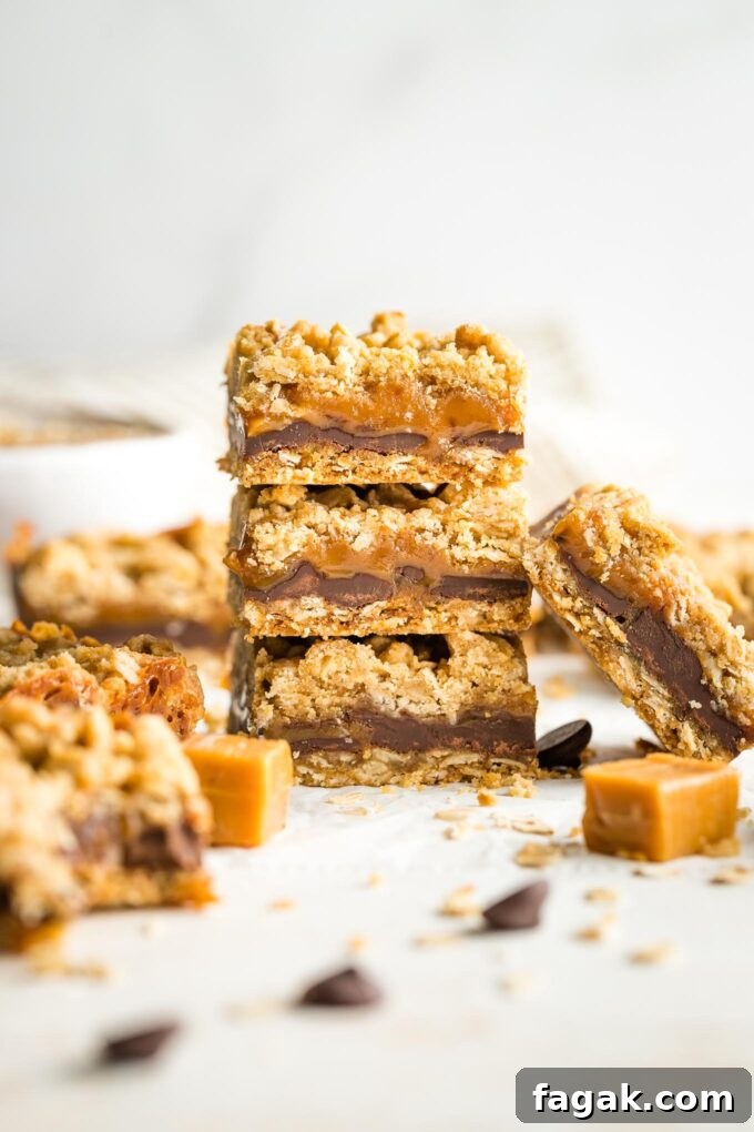 Stack of thick, chewy carmelita cookie bars surrounded by extra chocolate chips and caramels.