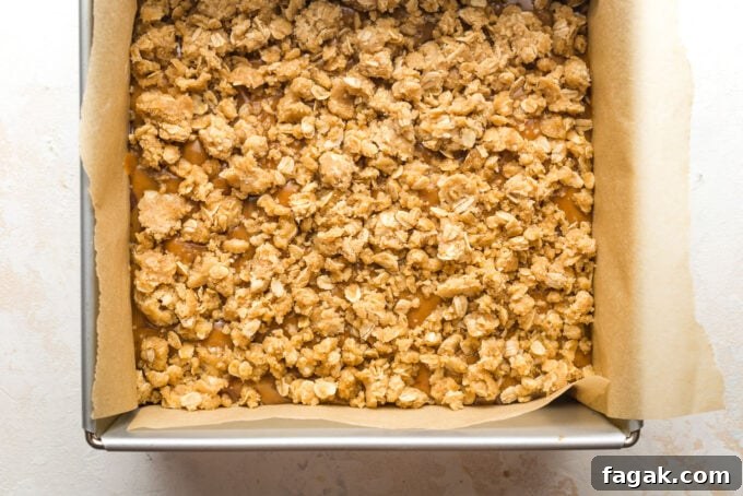 Baked bars with remaining oat cookie crust scattered on top of caramel layer.