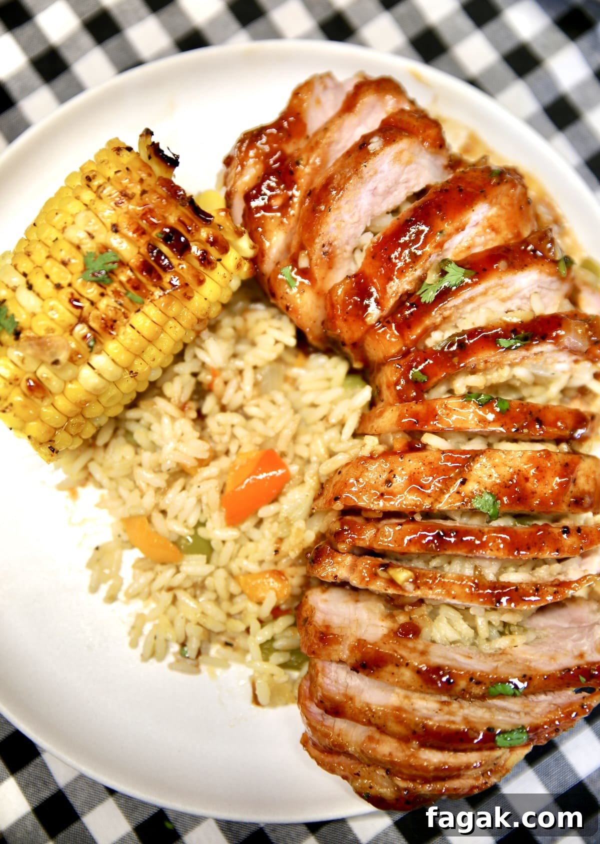 Plate with bbq sliced pork chop with rice and corn.