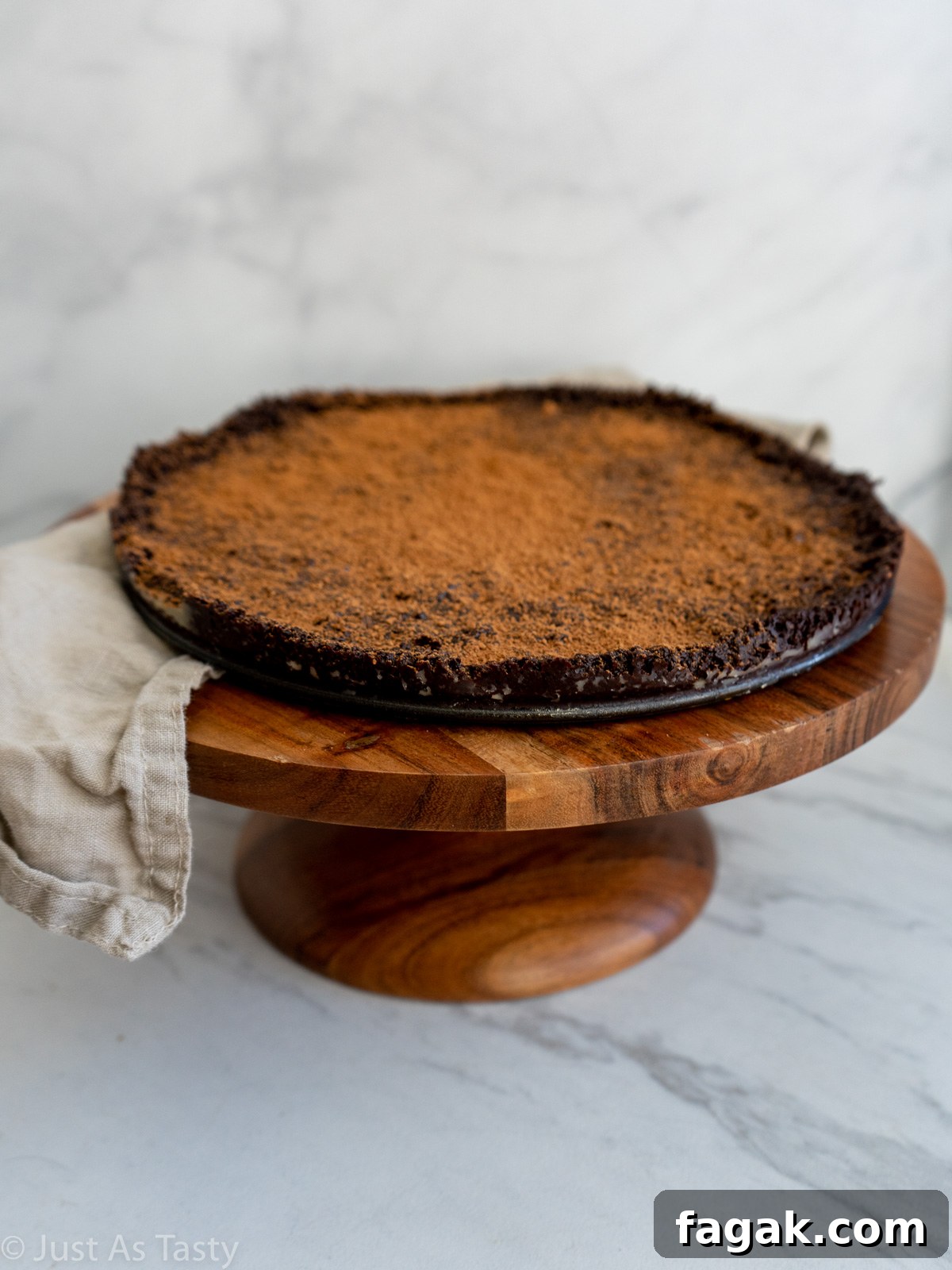 Flourless chocolate cake dusted with cocoa powder on a brown cake stand.