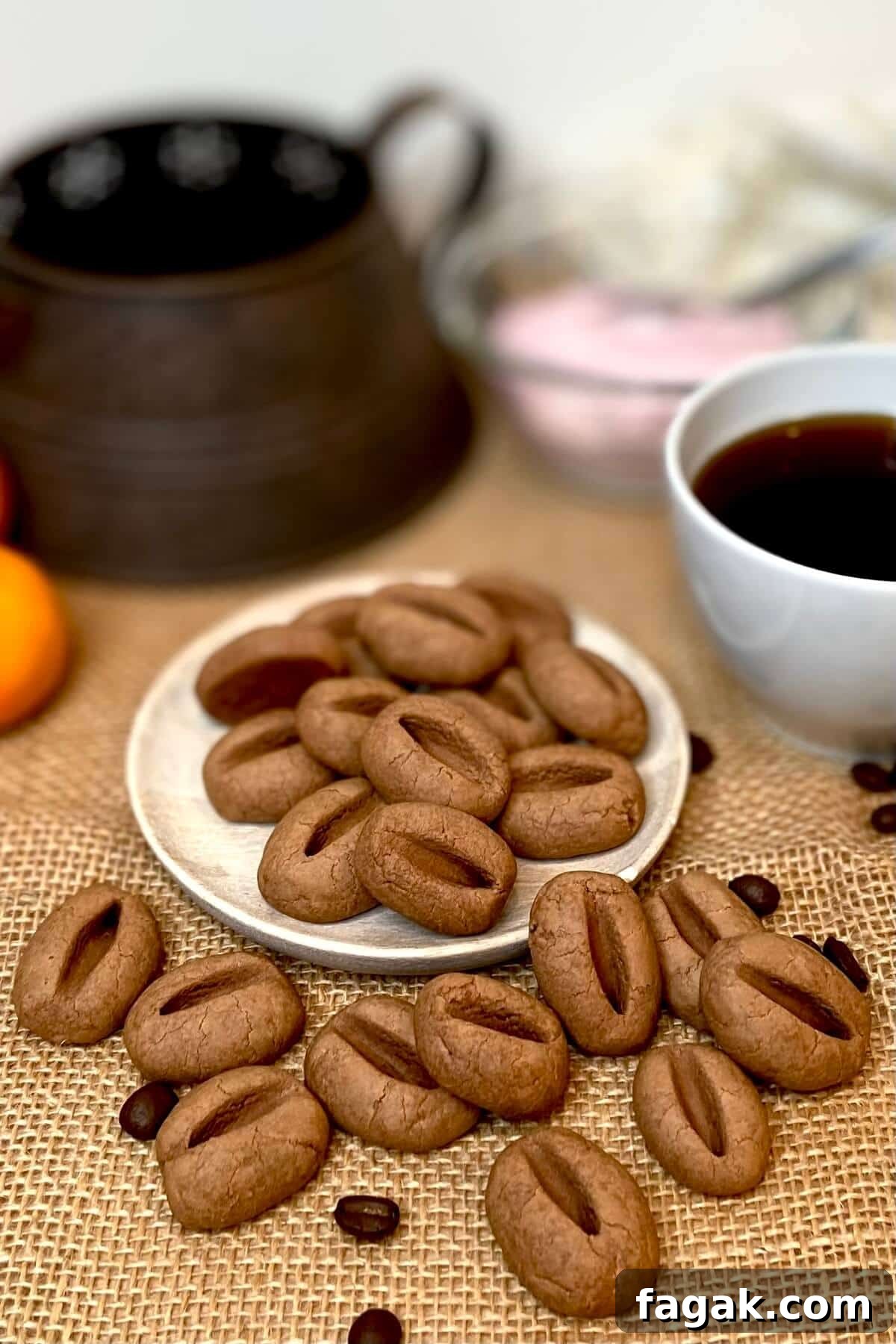 Cookies on a plate, with coffee beans sprinkled around and a cup of coffee.