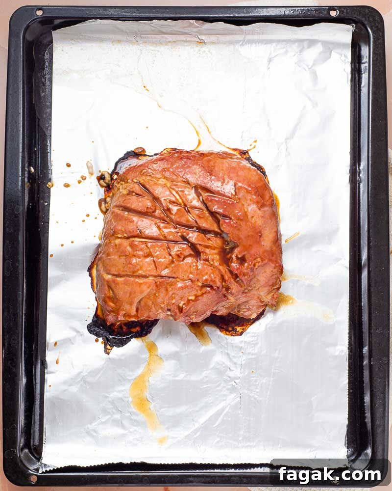 Spoon glazing the ham.
