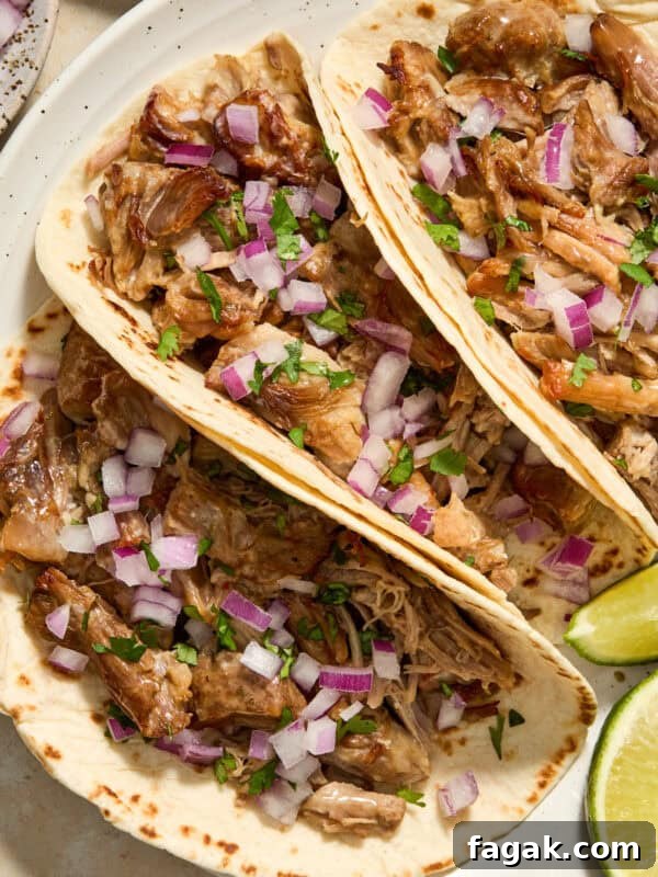 Instant Pot carnitas in tortillas with onion and cilantro on white dish.