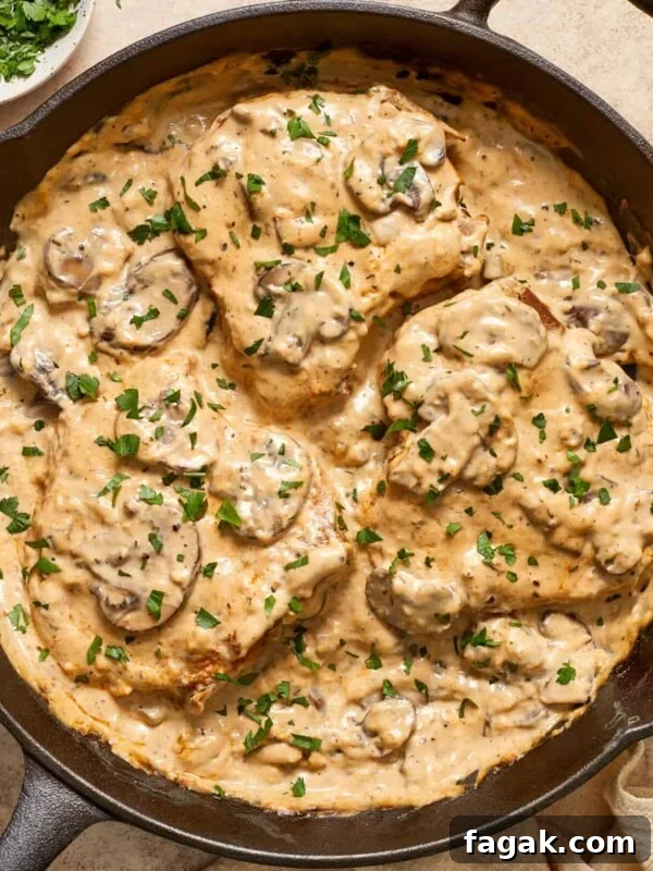 Skillet with cream of mushroom pork chops topped with chopped parsley.