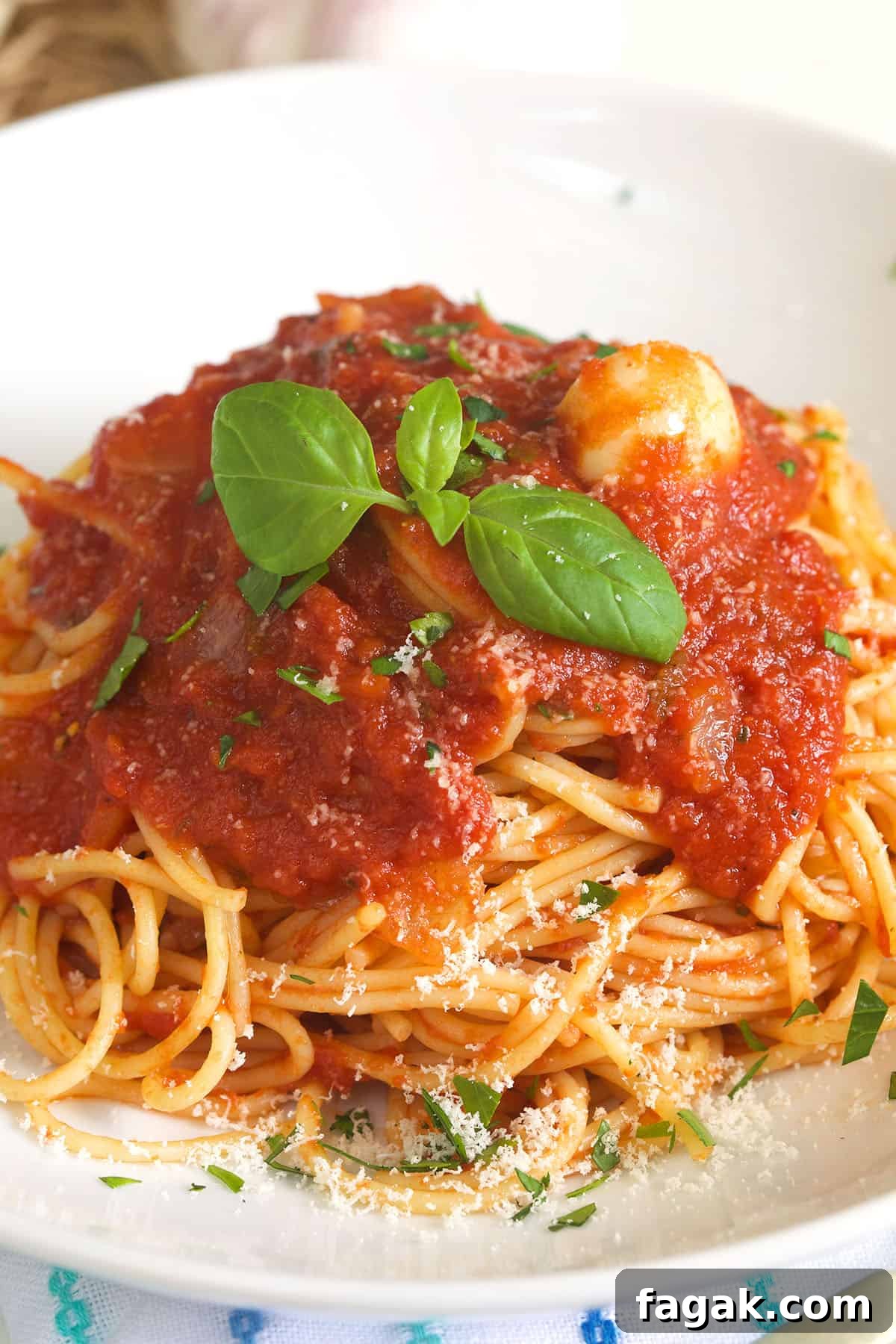 A serving of spaghetti is topped with marinara sauce and fresh herbs.