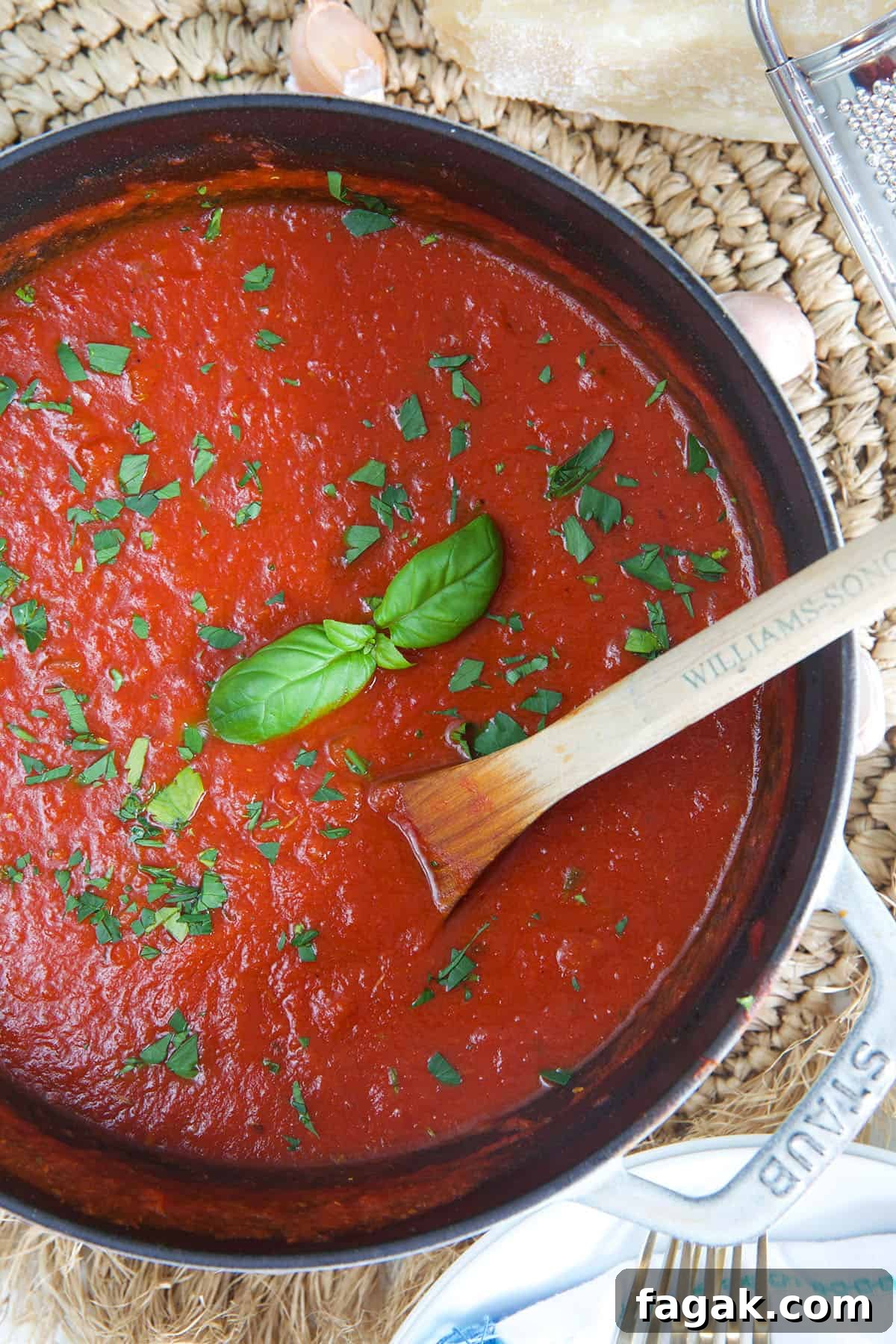 A large pot filled with red marinara sauce is being mixed with a wooden spoon.