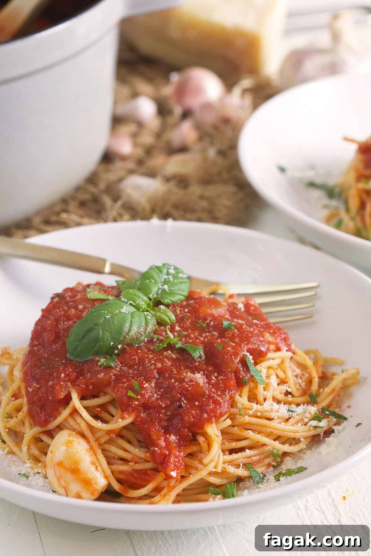 A fork is placed on a plate next to a serving of spaghetti.