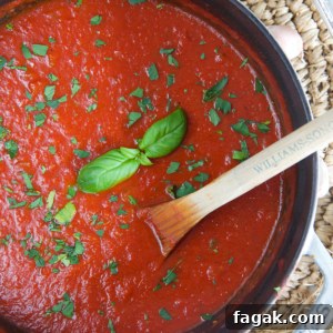 A large pot filled with red marinara sauce is being mixed with a wooden spoon.