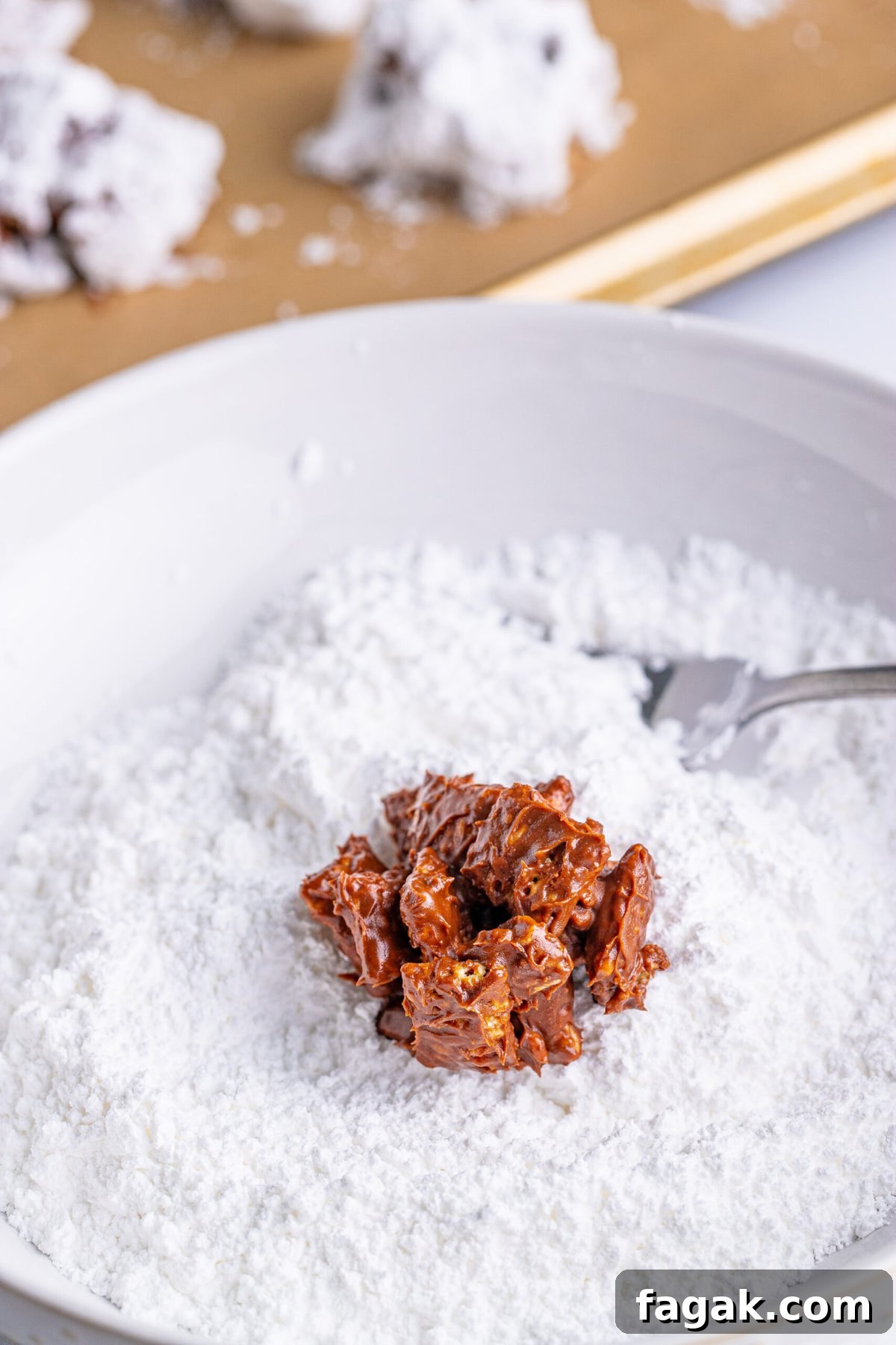 picture of muddy buddy cluster being dipped in powdered sugar