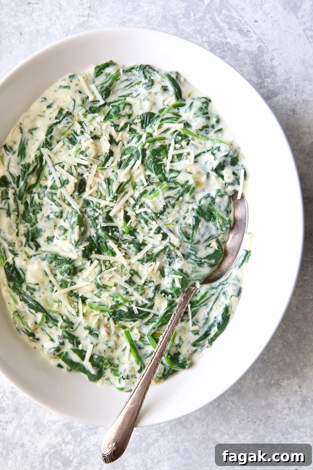 Steakhouse Creamed Spinach in white oval bowl with serving spoon.