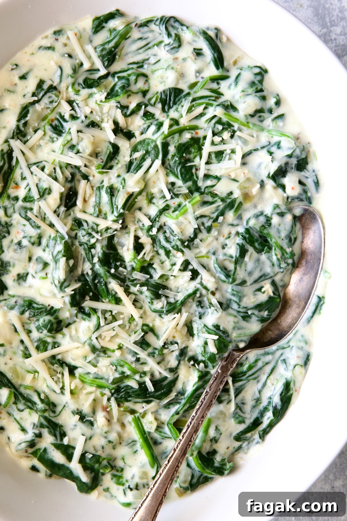 Steakhouse Creamed Spinach in white oval bowl with serving spoon.