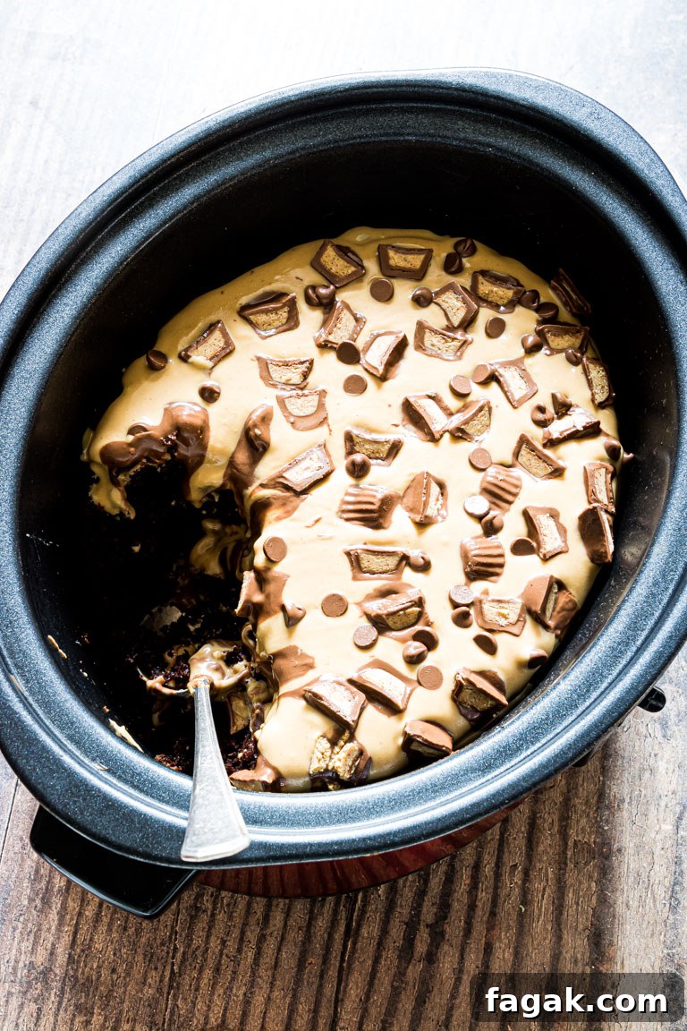 the finished crockpot peanut butter chocolate cake inside the crockpot with a serving removed