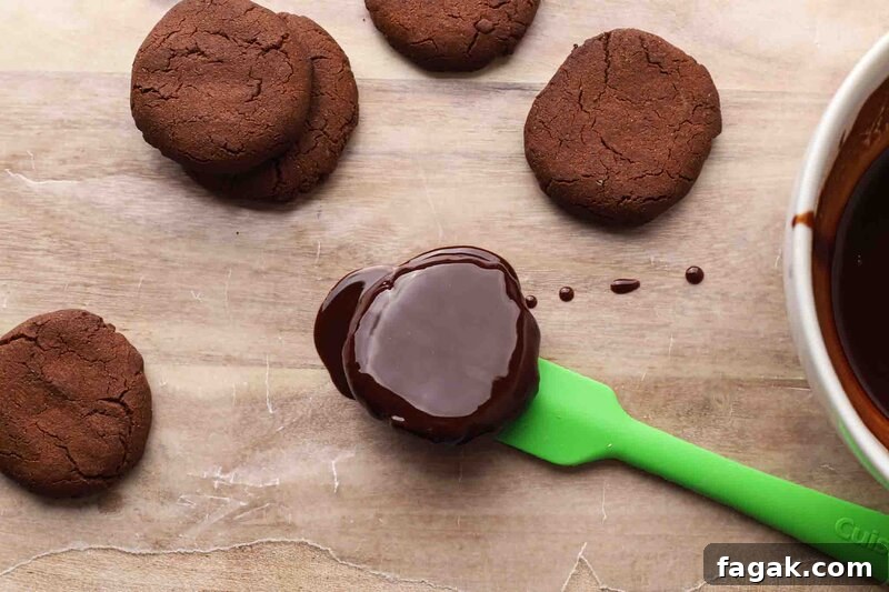 Coating a cookie with chocolate icing.